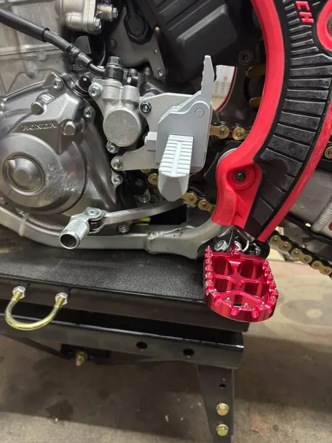 Grey 3D-printed prototype next to a red CNC-machined footpeg